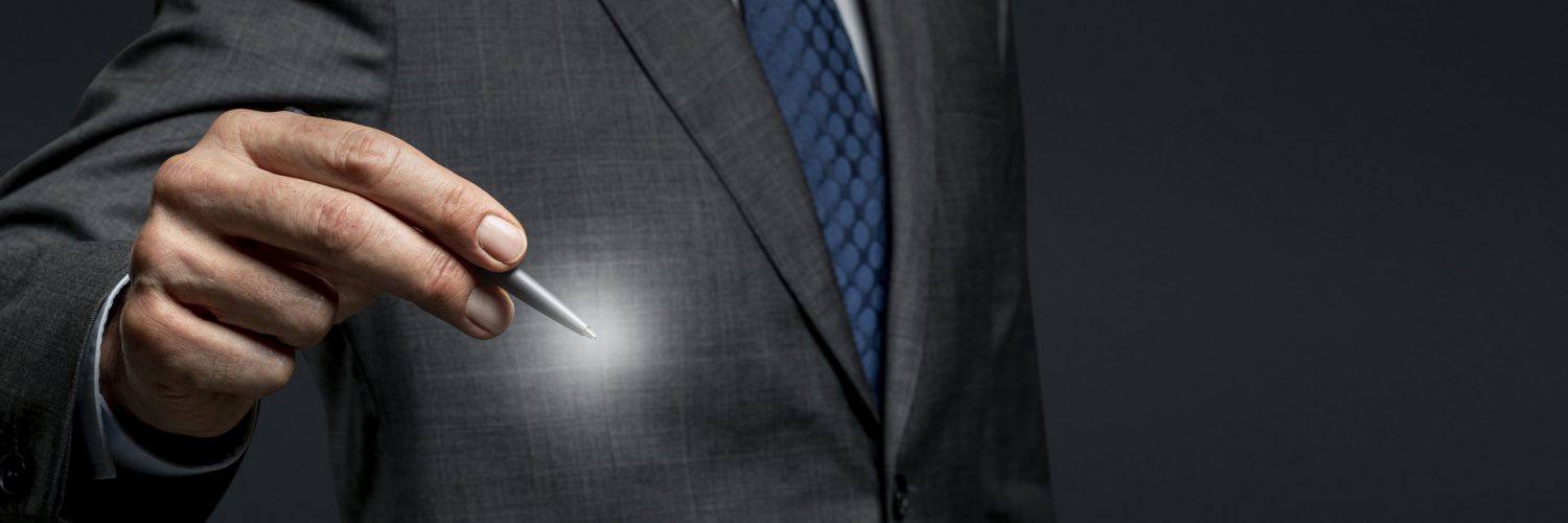 Businessman using a pen and signing on an invisible screen Businessman using a pen and signing on an invisible screen